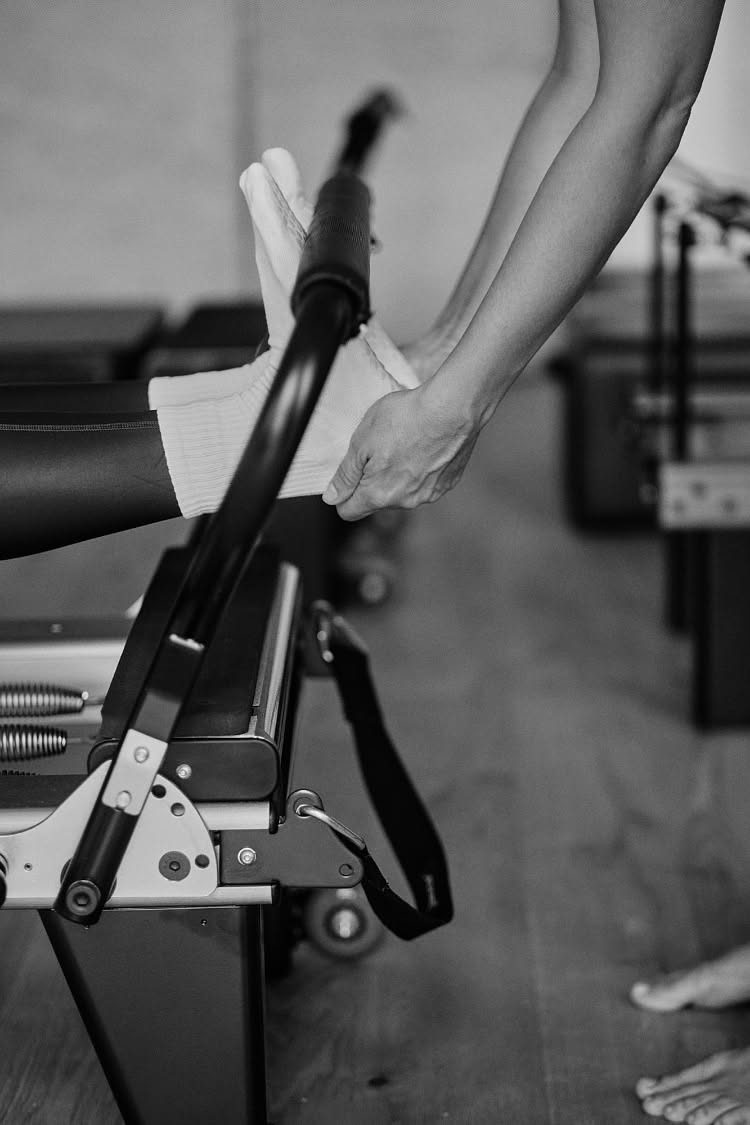 Hands guiding a leg on a Pilates reformer during a physio Pilates session